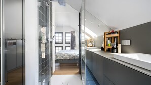 Een moderne badkamer met een douche, een grote spiegel en een wastafel.