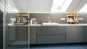 Een moderne badkamer met dakramen, een grote spiegel en een witte wastafel.