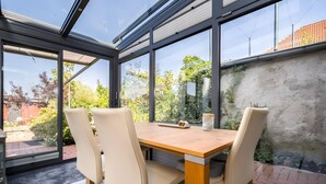 Een moderne eetruimte met een glazen wand, een houten tafel en twee stoelen.