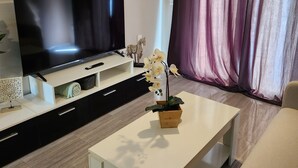 Un salon moderne avec un téléviseur à écran plat, une table basse, un canapé et une orchidée en pot.