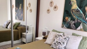 Une chambre d’hôtel avec un lit, une table de chevet, une lampe, un tableau représentant un oiseau et une porte coulissante.