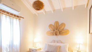 Une chambre à coucher avec un grand lit, deux tables de chevet avec des lampes, un ventilateur de plafond et un élément décoratif fixé au mur.
