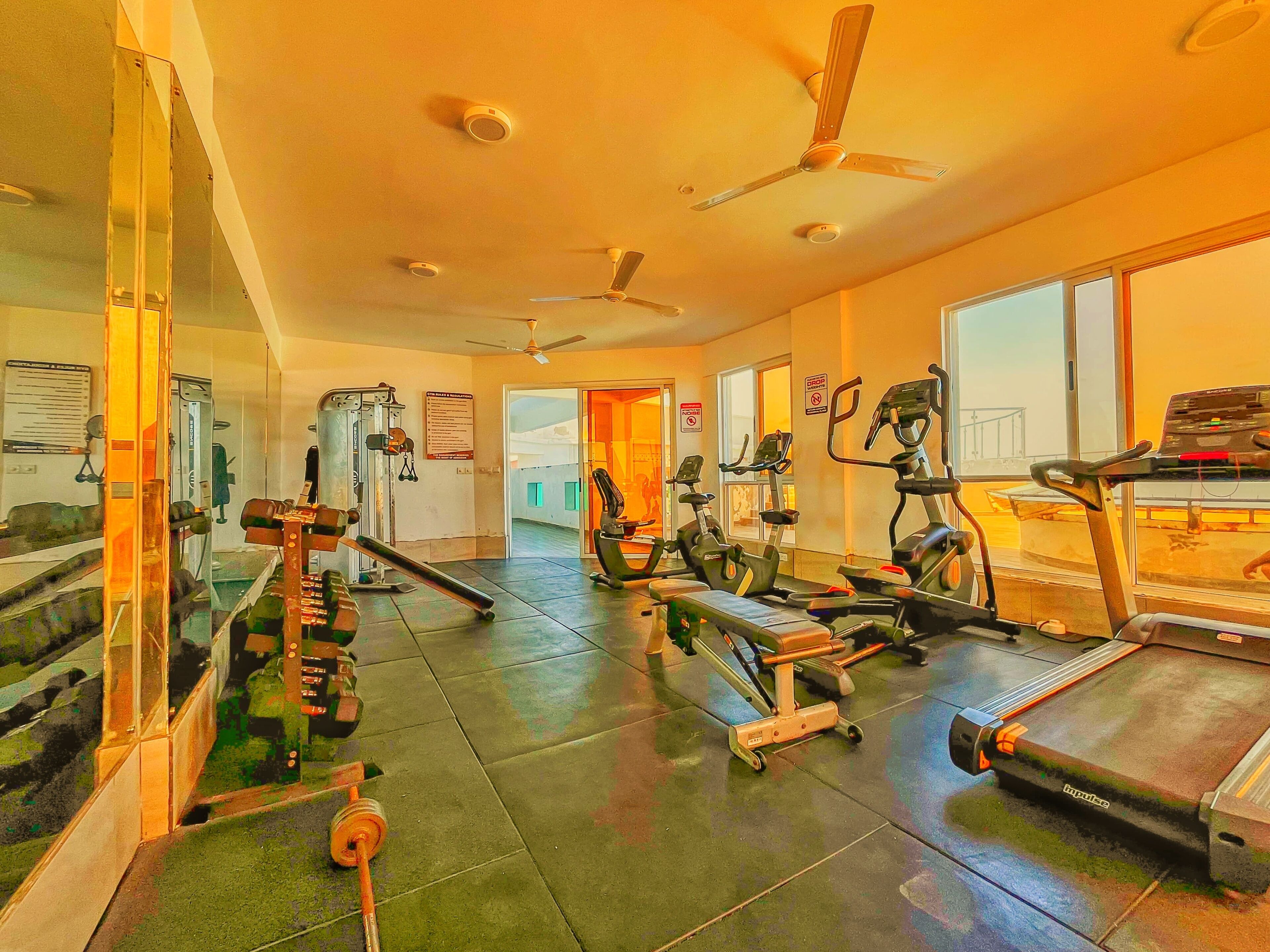 Et fitnesscenter med forskellig træningsudstyr, herunder løbebånd, motionscykler og styrkemaskiner.
