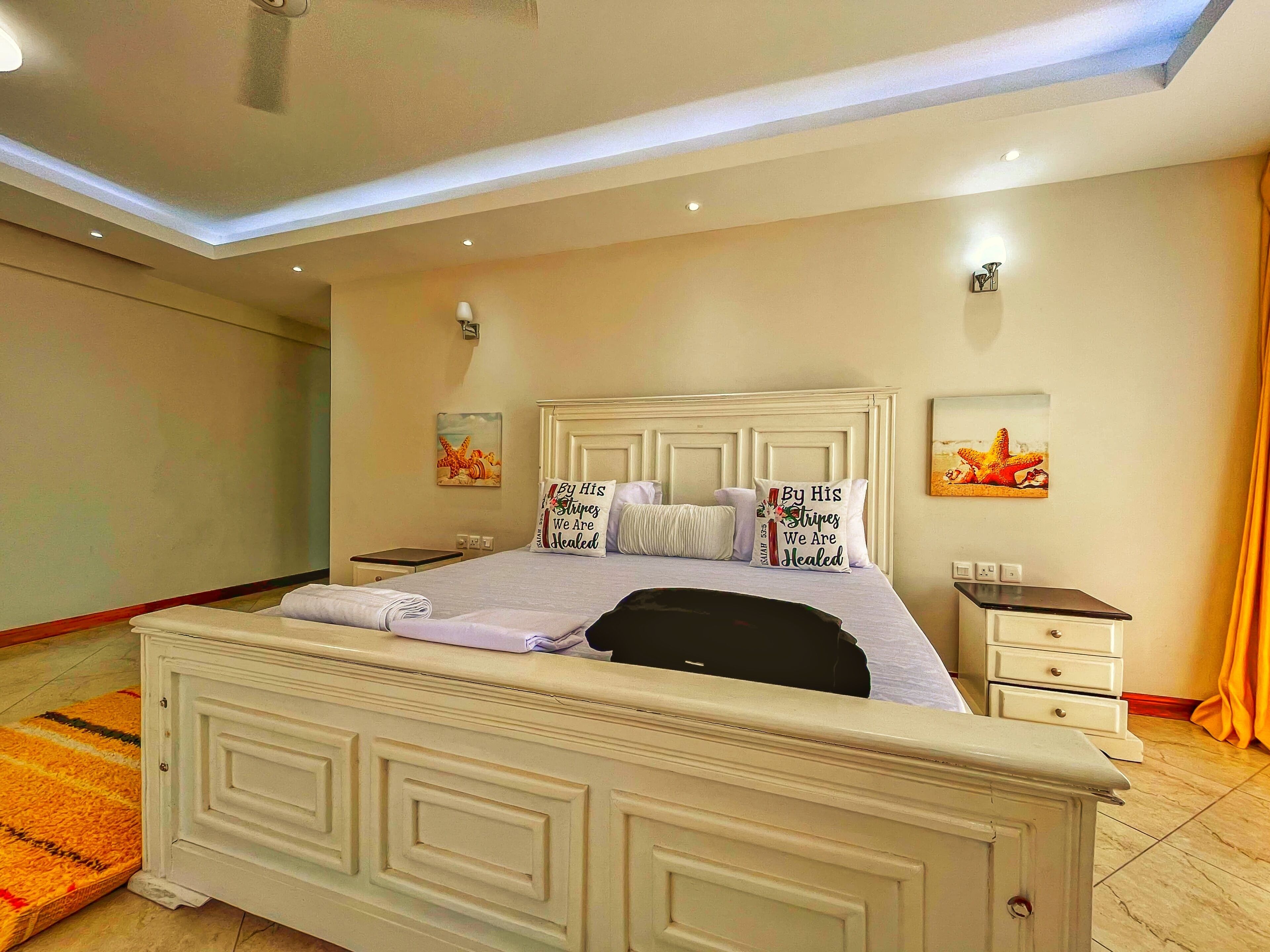 Un dormitorio con una cama grande, mesitas de noche y obras de arte en las paredes.