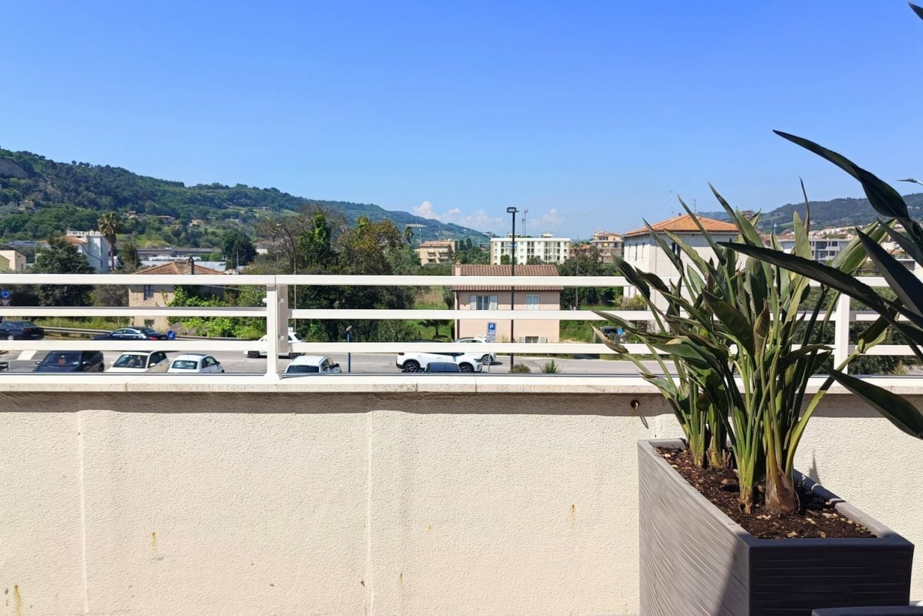 A balcony with a view of a parking lot and buildings in the distance.