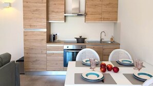 A compact kitchen with wooden cabinets, a built-in oven, and a dining area with a table set for four.