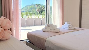 A hotel room with a bed, a window with curtains, and a view of a green landscape.