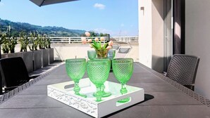 A table with green glassware and a white tray, set on an outdoor patio with a view of hills and a clear sky.