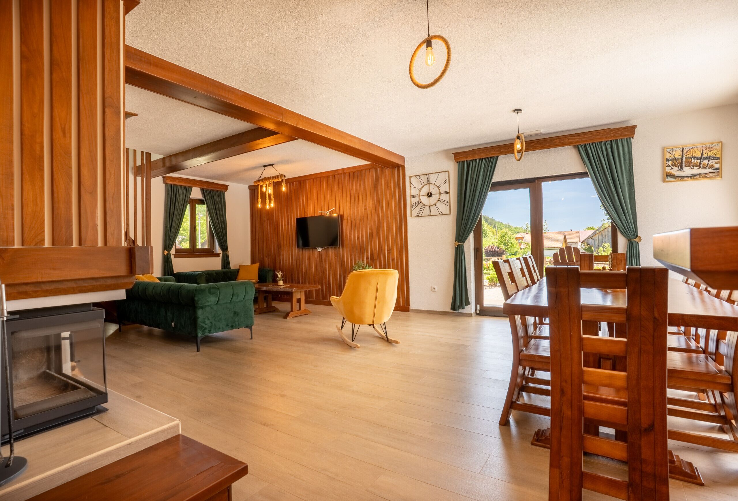 Un vaste espace de vie doté d’un plancher en bois, d’un canapé vert, d’un fauteuil à bascule jaune et d’une table à manger avec des chaises.