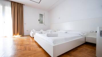 A modern hotel room with a large bed, a bedside table, a wardrobe, and a window with curtains.