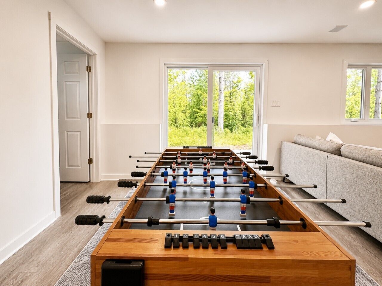 Ett fotbollsspelbord i ett rum med en soffa och en dörr.