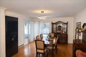 A dining room with a wooden table, chairs, a cabinet, and a television.