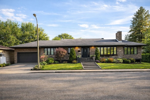 A modern single-story house with a garage, a front entrance with steps, and a well-maintained lawn.