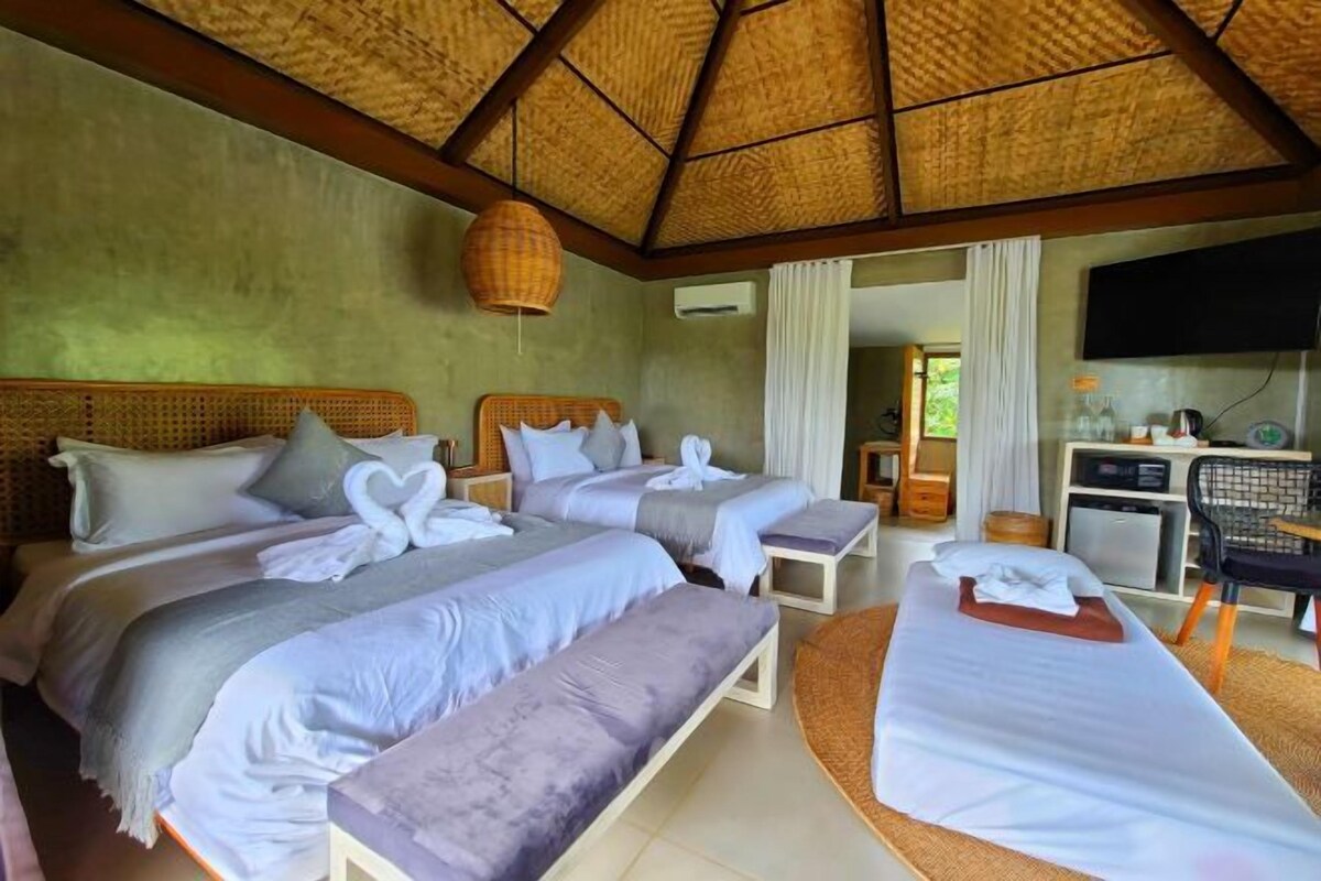Une chambre d’hôtel avec deux lits, un coin salon, une télévision et une kitchenette.
