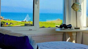 Une chambre avec vue sur l’océan, une table avec une lampe et une fenêtre avec des rideaux.