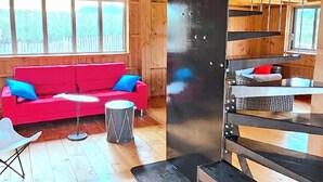 Un intérieur en bois avec un canapé rouge, une petite table et un escalier.