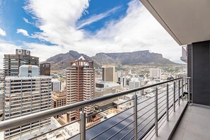 Un edificio de gran altura con un balcón que da a un paisaje urbano y montañas.