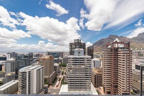 A cityscape with modern high-rise buildings, a prominent tower with a unique design, and a mountainous backdrop. - 16 On Bree Superior Apartment (Cape Town)