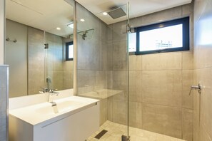 Ein modernes Badezimmer mit einer großen Badewanne, einer gläsernen Dusche und einem Fenster mit Tageslicht.