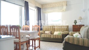 A living room with a sofa, a dining table with chairs, and a lamp.