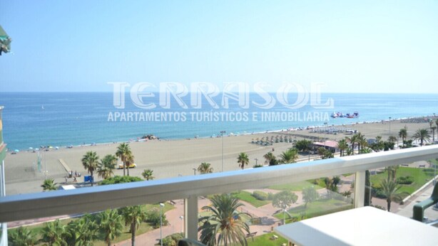A beach view from a balcony with a clear sky.