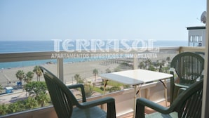 A balcony with a table and chairs overlooking a beach.