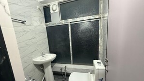 Un baño con un lavamanos pedestal blanco, un inodoro y una zona de ducha.