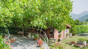 A stone pathway leading to a rustic house surrounded by lush greenery and flowering plants. - Cosy apartment for 6 guests with A/C, private pool, WIFI, TV and terrace (Casarza Ligure)