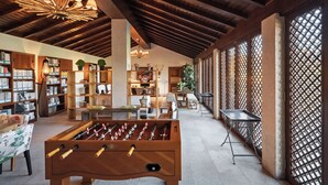 A spacious indoor area with a foosball table, bookshelves, and a dining area. - Casas da Memória (Tarouca)