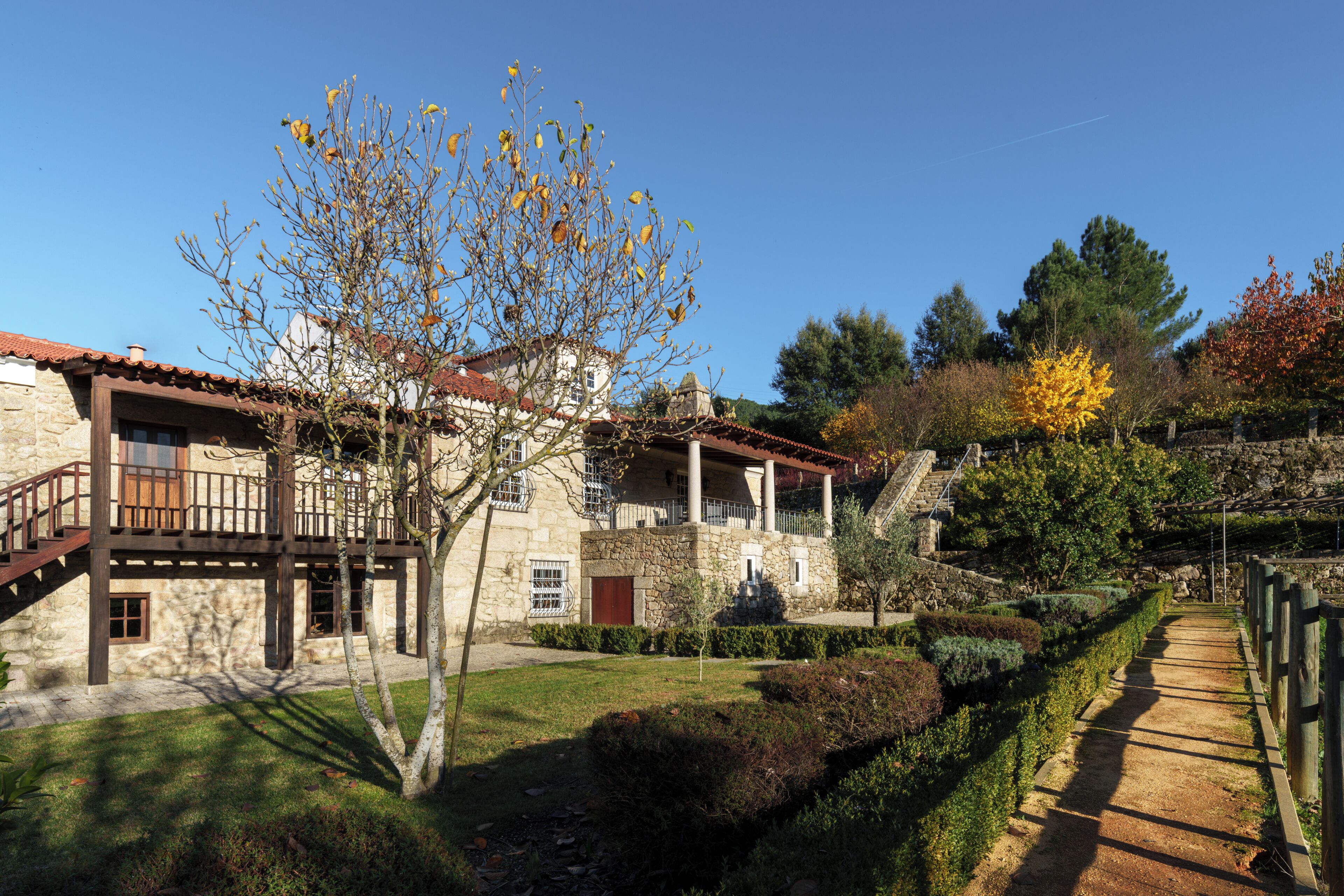 A stone building with a balcony, a staircase, and a pathway.
