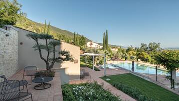 A patio area with outdoor seating, a swimming pool, and a view of the surrounding landscape.
