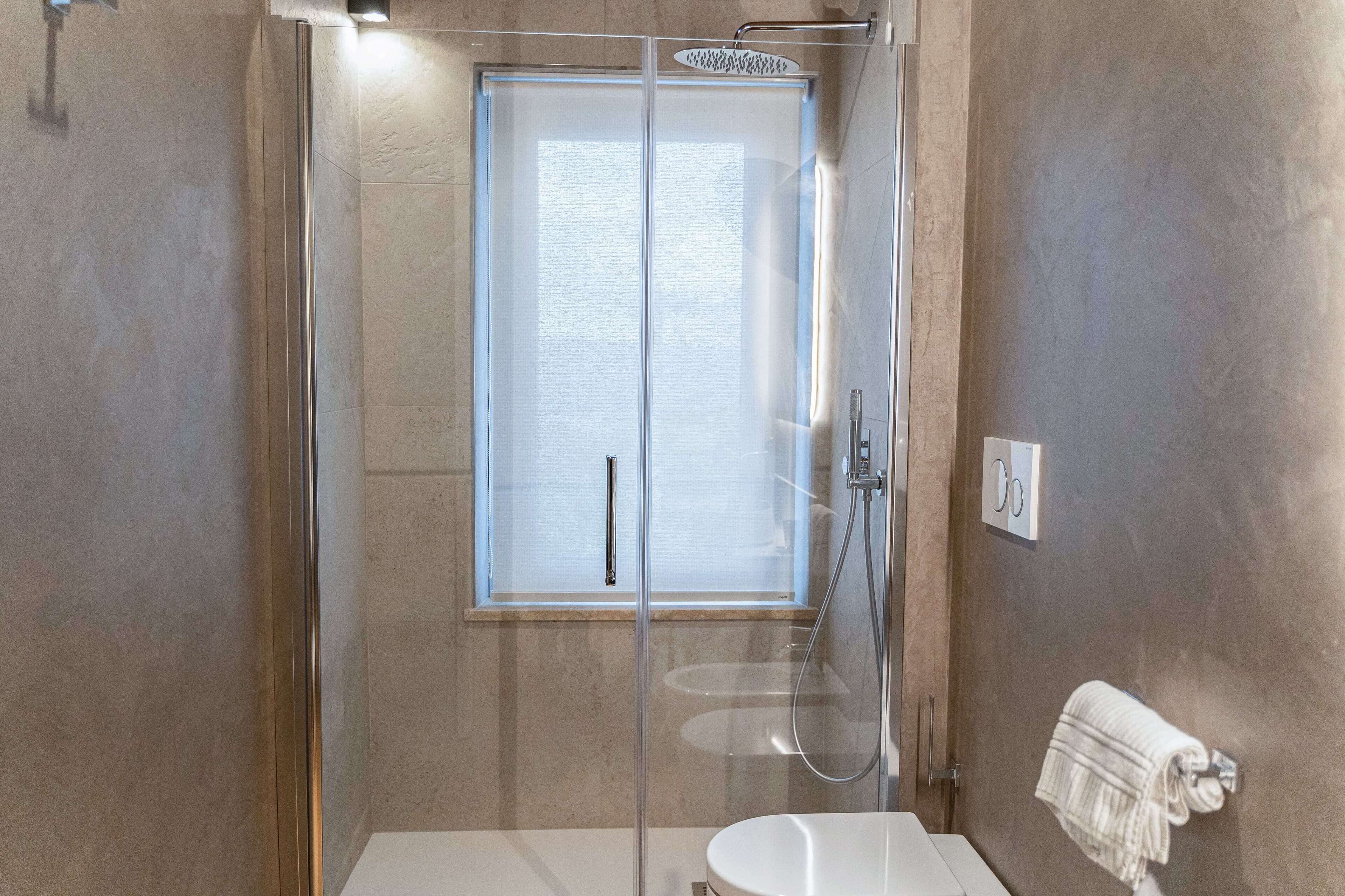 A modern bathroom with a glass-enclosed shower, a white sink, and a towel rack.