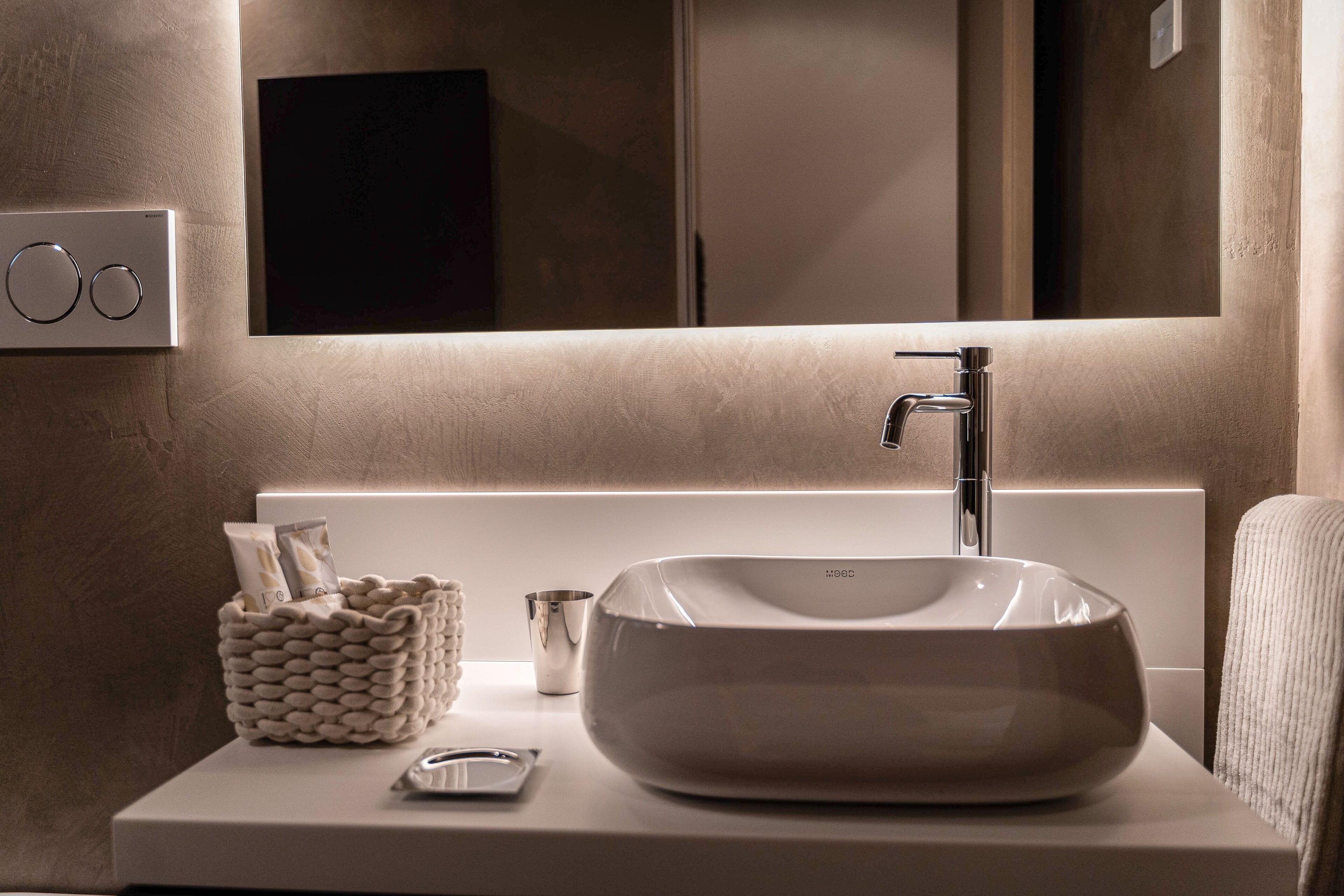 A modern bathroom with a large, oval sink, a mirror above the sink, and a wall-mounted light fixture.