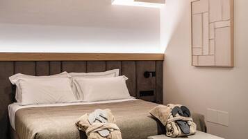 Un dormitorio con techo de madera, una cama con almohadas y dos otomanas.
