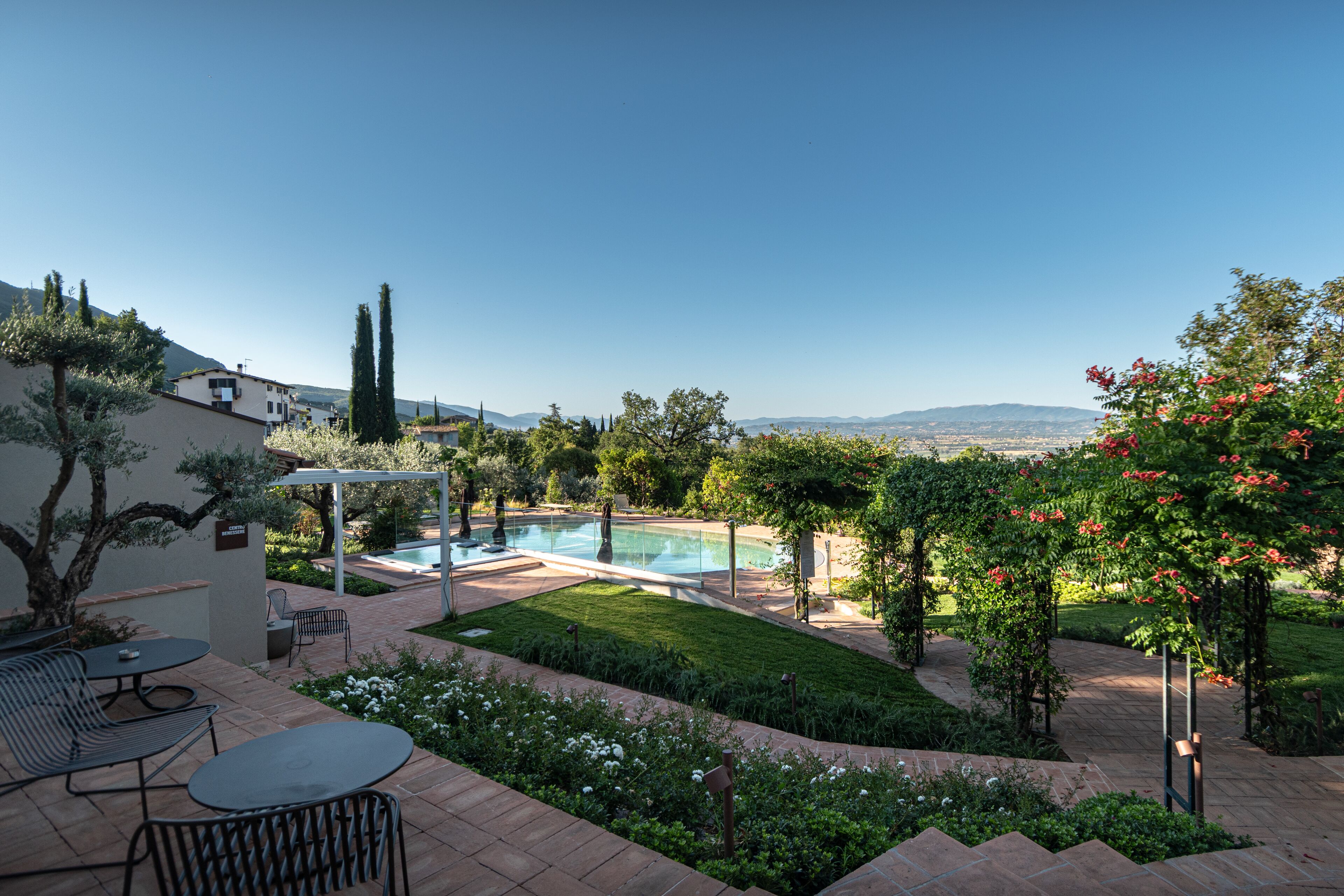 Un jardín trasero con piscina, muebles de patio y vistas a las montañas.