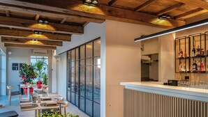 Un interno moderno con travi in legno, un'area bar e un salotto con tavoli e sedie.