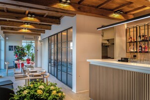 Un interior moderno con vigas de madera, una zona de bar y un área de estar con mesas y sillas.