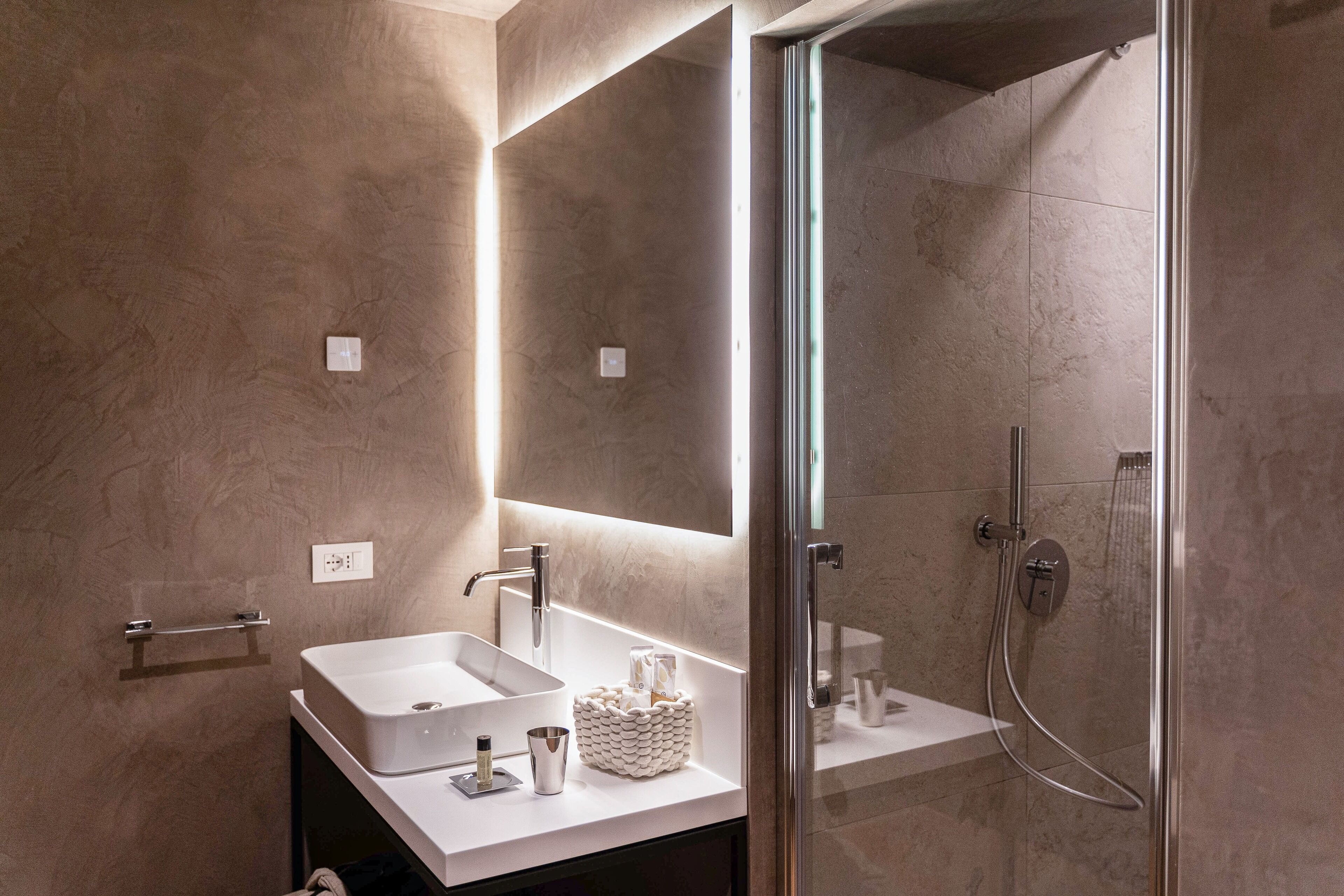 A modern bathroom with a large mirror, a sink, and a shower.