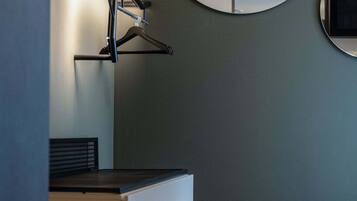A modern room with a wooden floor, a black desk, a white cabinet, and two round mirrors on the wall.