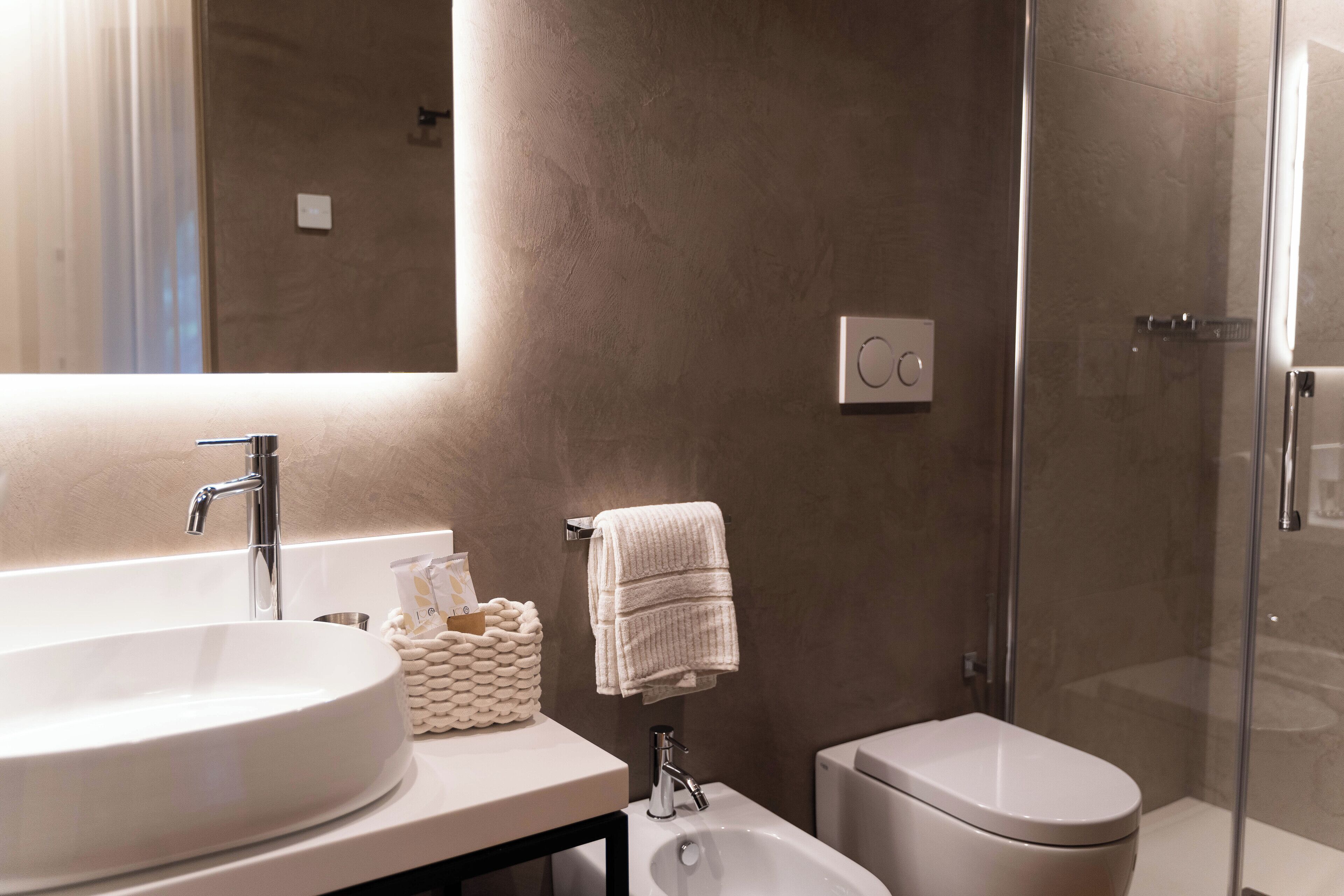 Een badkamer met een groot ovaal wastafel, toilet en een douche met glazen wand.