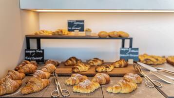 A display of assorted pastries and croissants on wooden boards, with signs indicating different types of baked goods.
