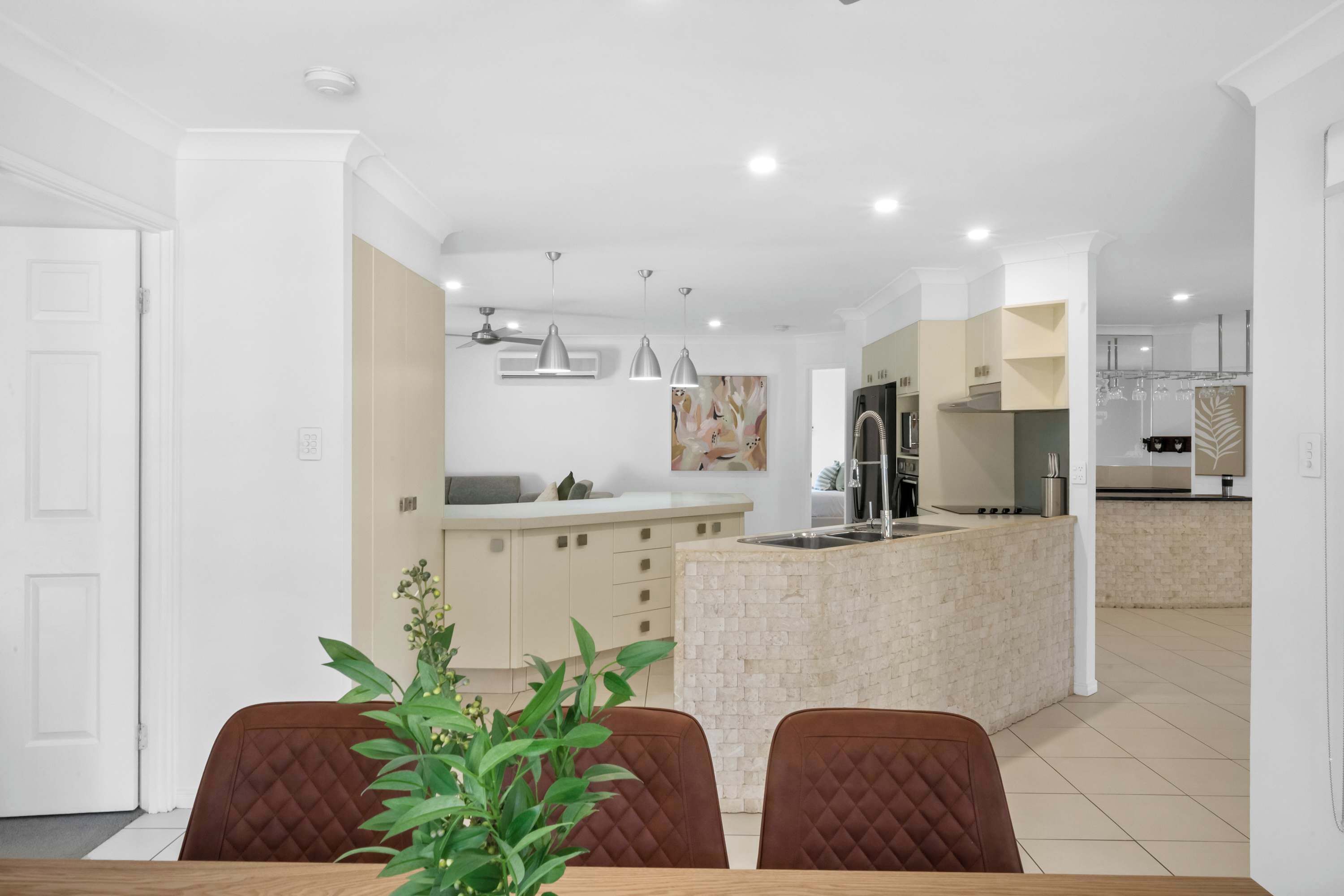 Una cucina moderna con isola centrale, illuminazione a sospensione e zona pranzo con tavolo e sedie.