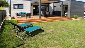 Une maison moderne dotée d’un patio couvert, d’une terrasse et d’un petit jardin.