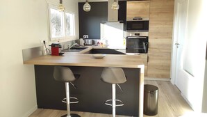 Une cuisine moderne dotée d’un îlot central, de tabourets de bar, d’un four à micro-ondes et d’un four traditionnel.