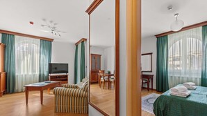 Ein Hotelzimmer mit einem großen Bett, einem Fernseher, einem Esstisch und einem gestreiften Sessel.