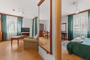 Une chambre d’hôtel avec un grand lit, une télévision, une table à manger et un fauteuil à rayures.