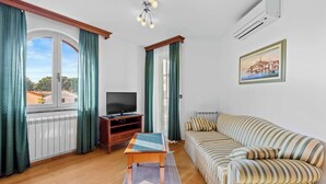 Ein Wohnzimmer mit einer Couch, einem Fernseher, einem Holztisch und einer Heizung.