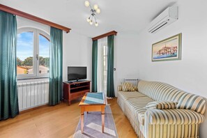 Un salon avec un canapé, un téléviseur, une table en bois et un radiateur.
