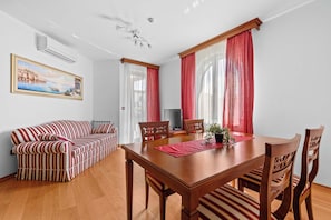 Ein Essbereich mit Holztisch, Stühlen, einer Couch und einem Fernseher.