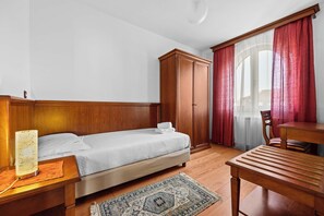 Ein Schlafzimmer mit Bett, Holzschrank, Tisch und Stuhl.
